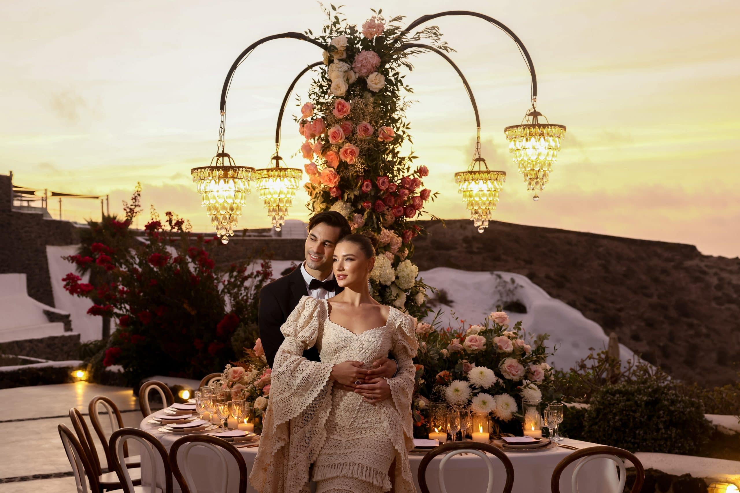 An intimate sunset wedding dinner in Santorini with chandeliers and florals
