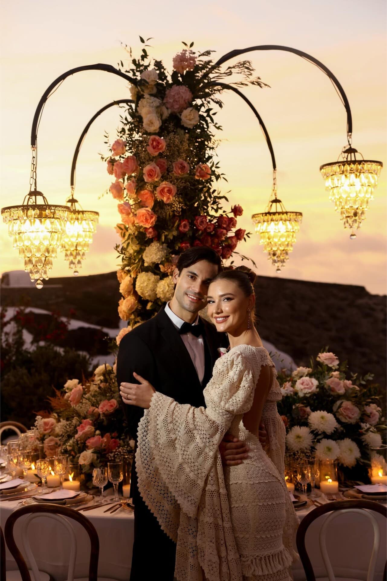A couple embracing at a candlelit Santorini wedding at sunset