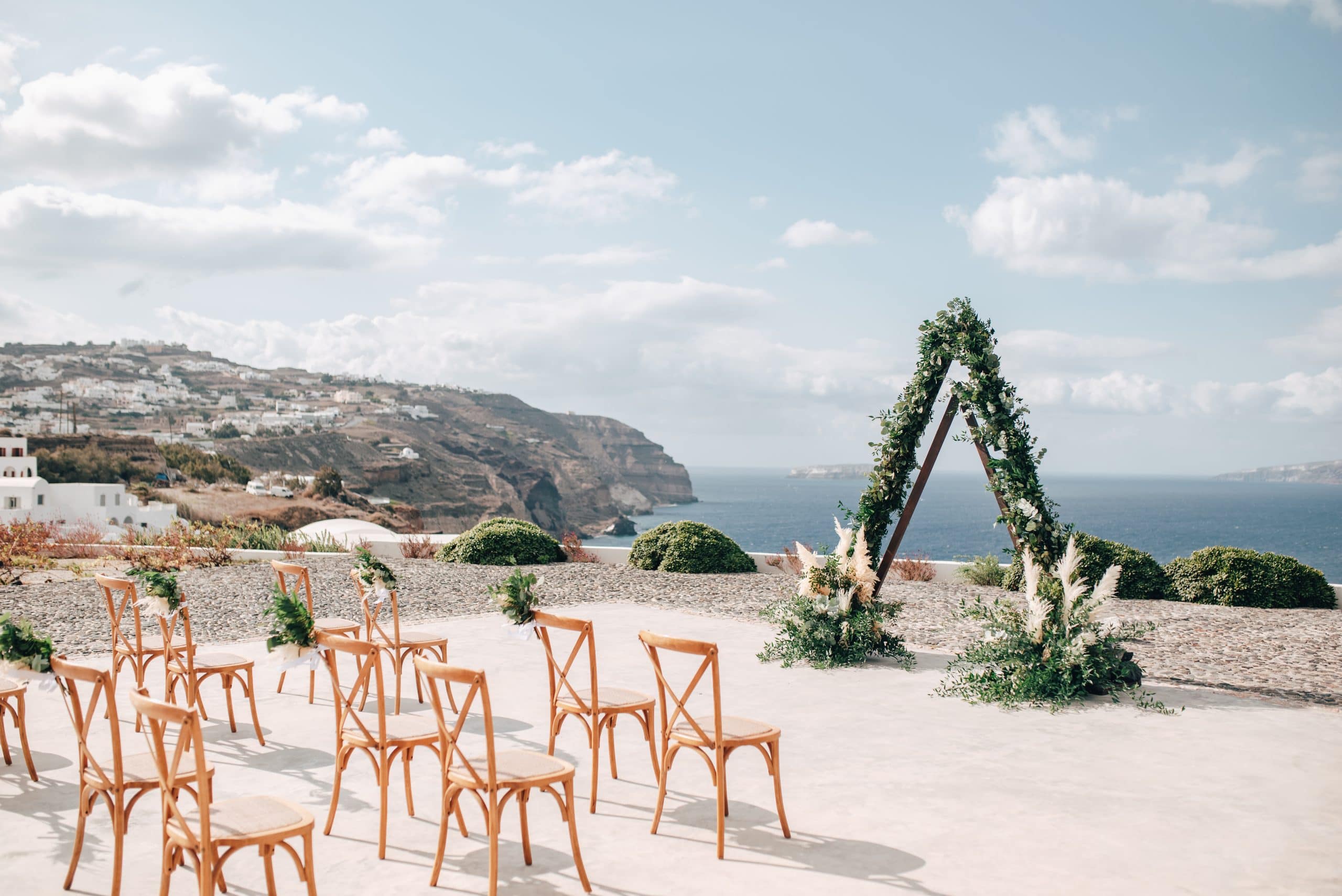 A wedding ceremony set up on a Santorini terrace overlooking the sea